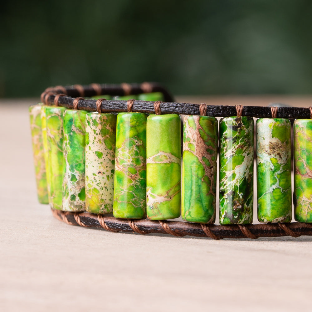 This single wrap bracelet features dark green Jasper stones in tube-shaped cuts, set against a genuine leather band for a stunning contrast