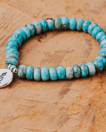 Treehut's stretchable bracelet with turquoise stone beads and a silver buddha charm in the center