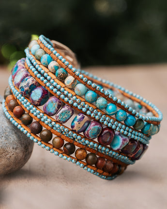 A handmade three-wrap bracelet featuring sea sediment jasper stones in shades of blue and purple